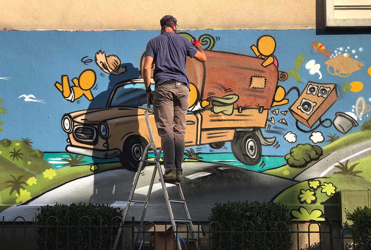 L'artiste Jace, sur un escabeau, peint une fresque à la bombe le mur rue Henri Roy à Orléans